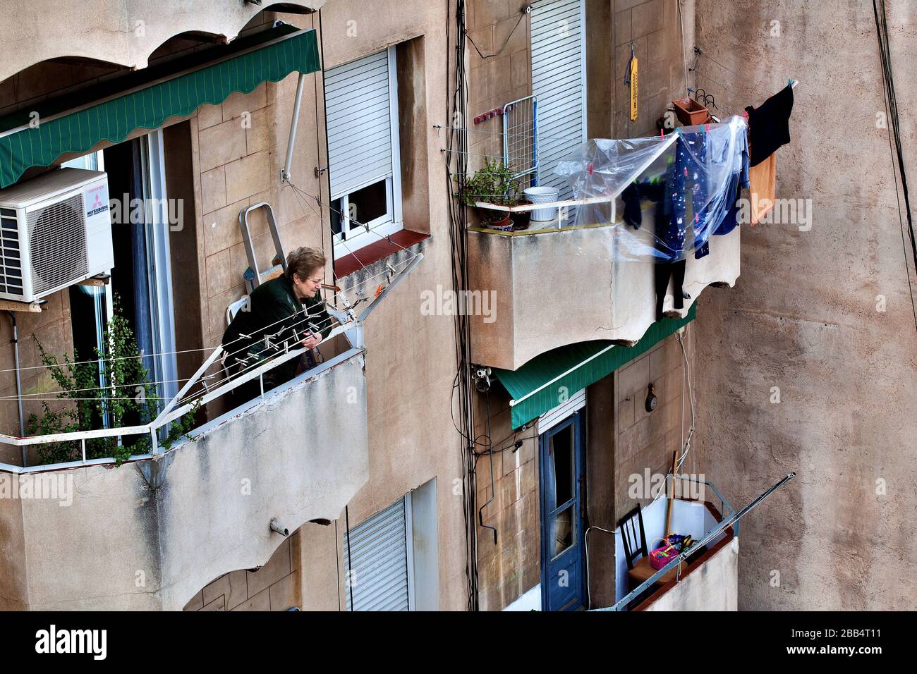 Una donna anziana prende un breve sguardo dal suo balcone durante la seconda settimana del blocco di coronavirus a Barcellona, Spagna. Foto Stock