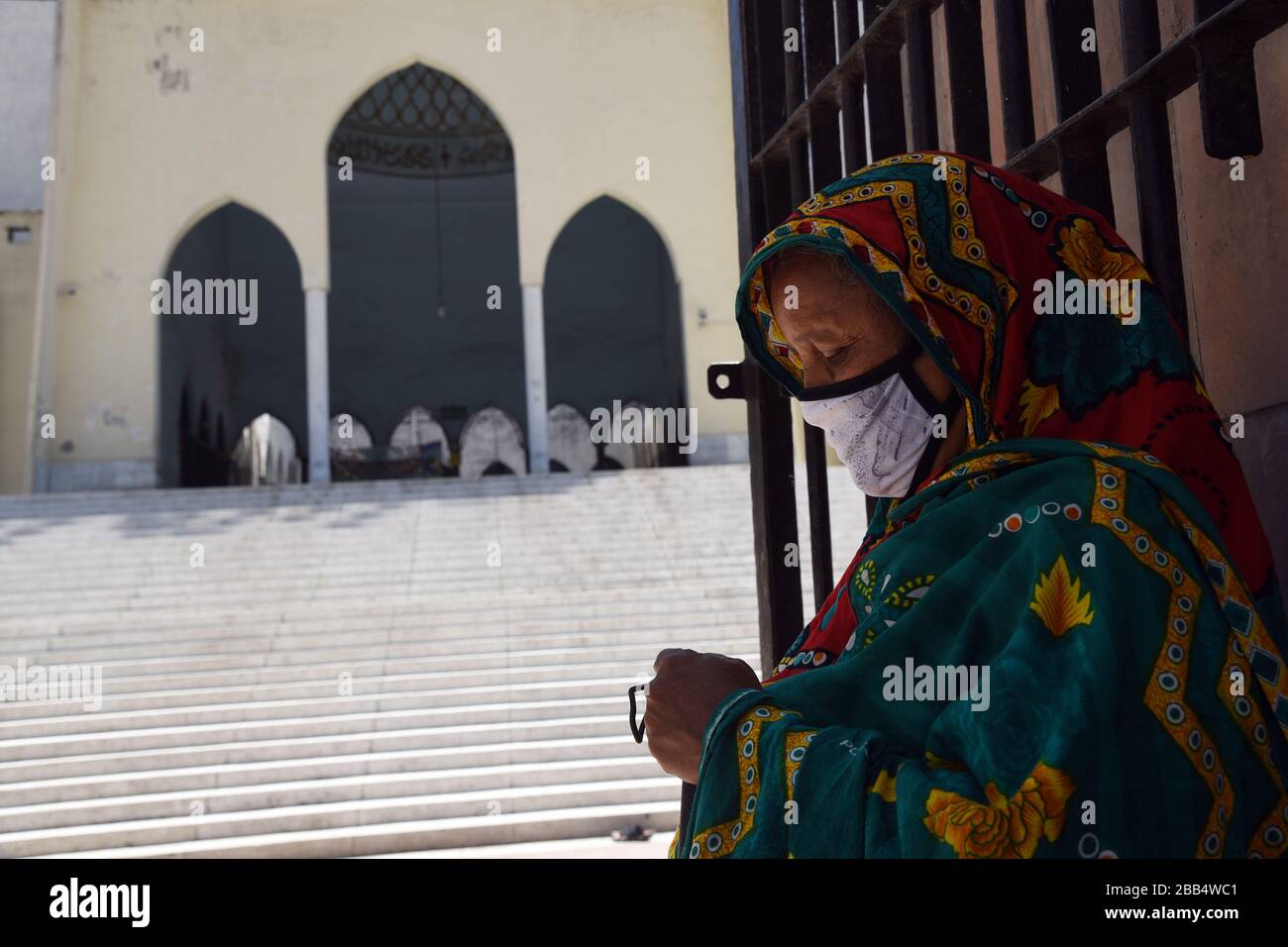 Un mendicante cieco donna indossa una maschera facciale sulla Moschea Nazionale di Baitul Mukarram a causa dell'attuale pandemia di COVID-19 a Dhaka il 29 marzo 2020. Foto Stock