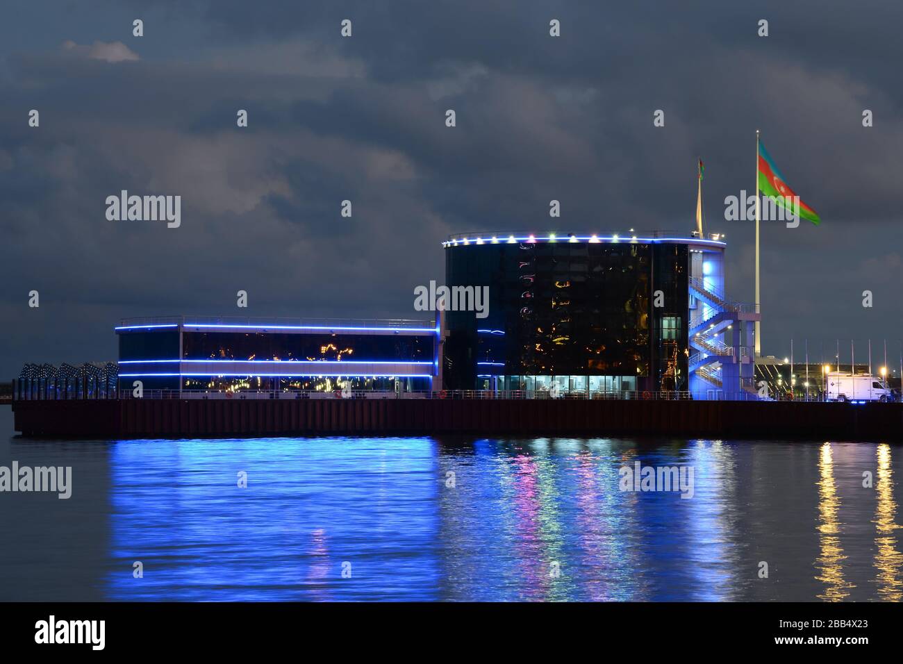 Yacht Club Baku di notte / ora blu. Hotel Blue Sail Yacht Club visibile con onde del Mar Caspio che riflettono le luci. Azerbaigian palo bandiera visibile. Foto Stock