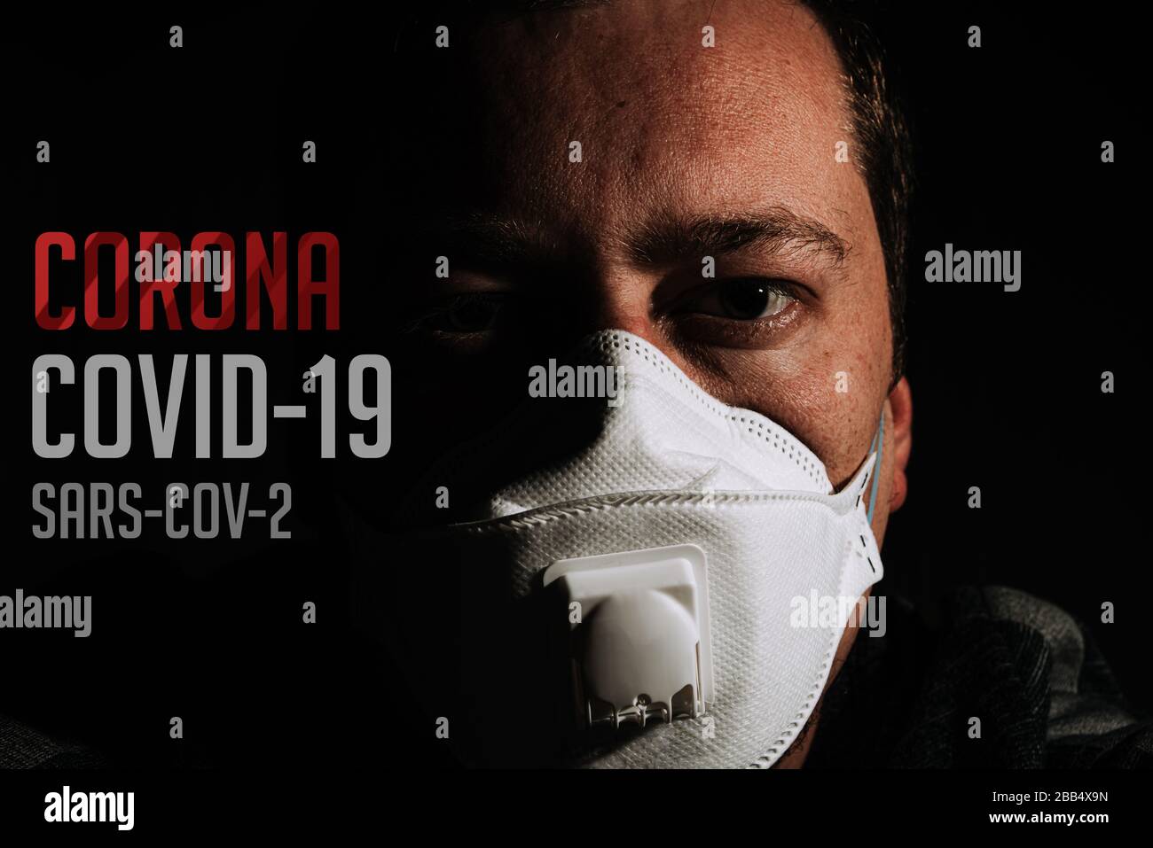 uomo con maschera respiratore per protezione coronavirus covid-19 su sfondo nero con testo Foto Stock