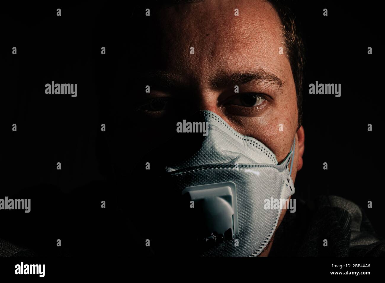 uomo con maschera respiratore per protezione coronavirus covid-19 su sfondo nero Foto Stock
