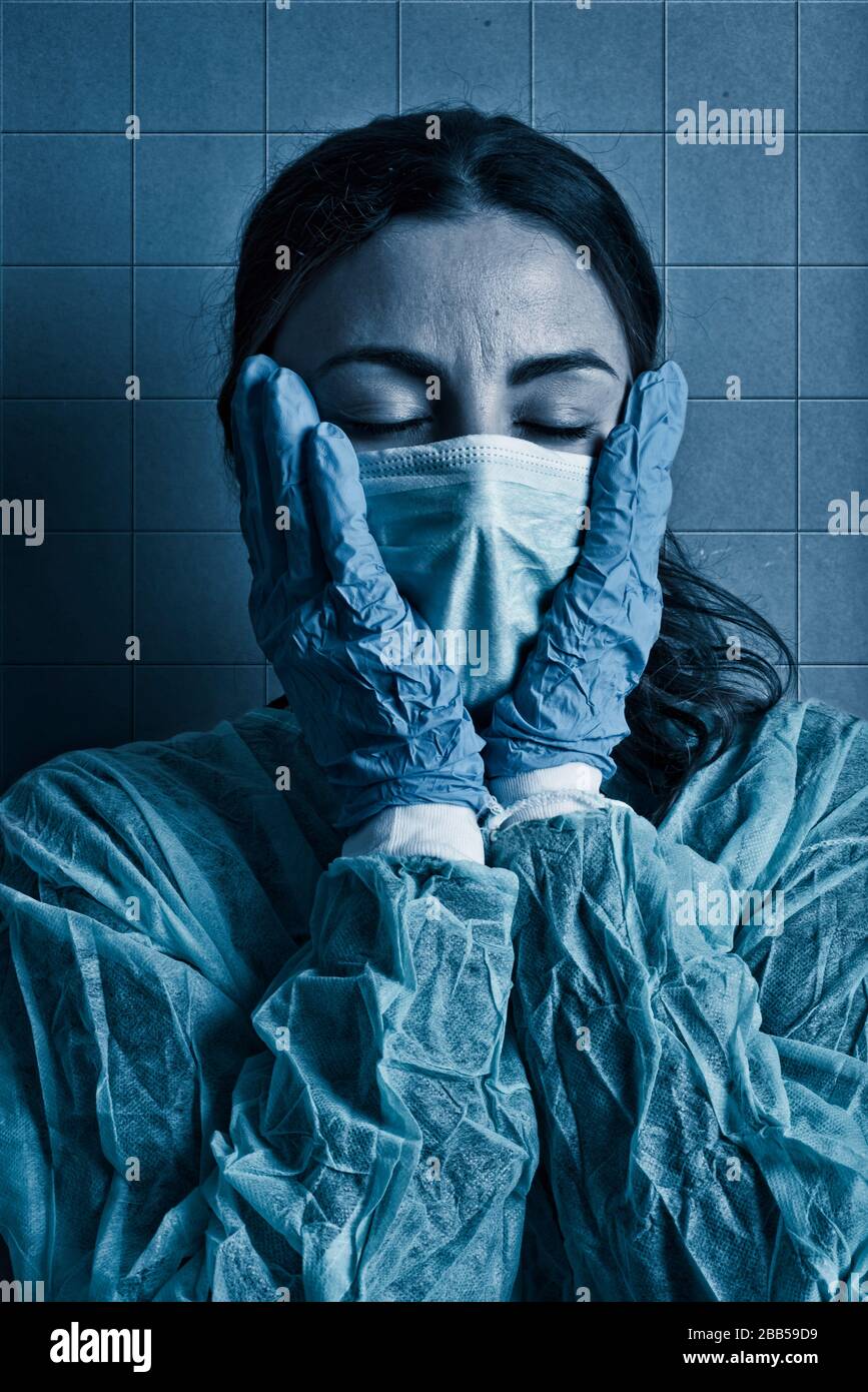 infermiere stanco che tratta pazienti con coronavirus, con maschera protettiva e mani sul viso Foto Stock