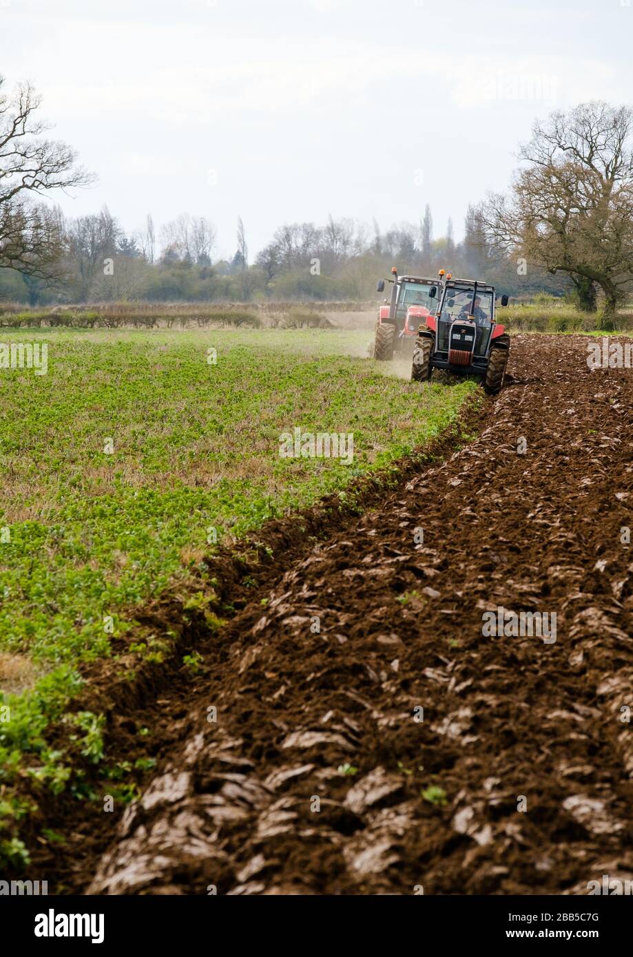 Due trattori che arano un campo nel Warwickshire, Regno Unito Foto Stock