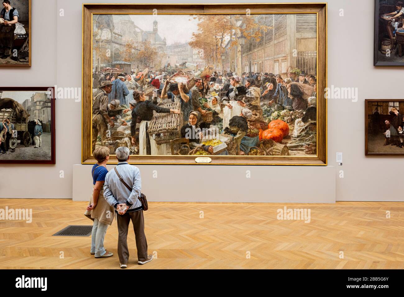 Coppia che guarda la pittura su larga scala 'le Halles' di Leon l'Hermitte (1895), in mostra al Petit Palais, Parigi, Francia Foto Stock