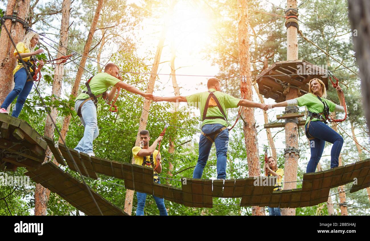 Gruppo arrampicata insieme nella foresta di arrampicata come un evento di team building Foto Stock