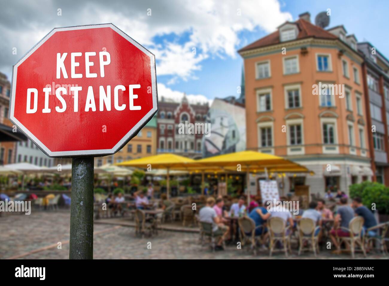 Concetto di distanza sociale. Cartello con la parola Keep Distance con caffè con sfondo sfocato persone. Misure preventive per il contenimento del virus corona Foto Stock