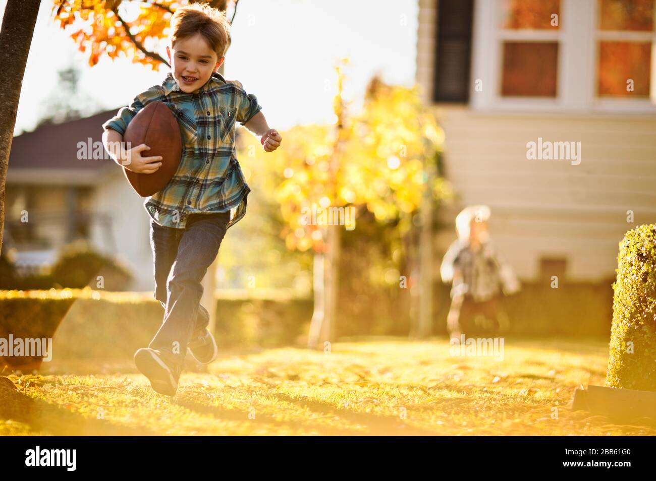 Esecuzione di ragazzo giocando a calcio nel cortile con il suo fratello. Foto Stock