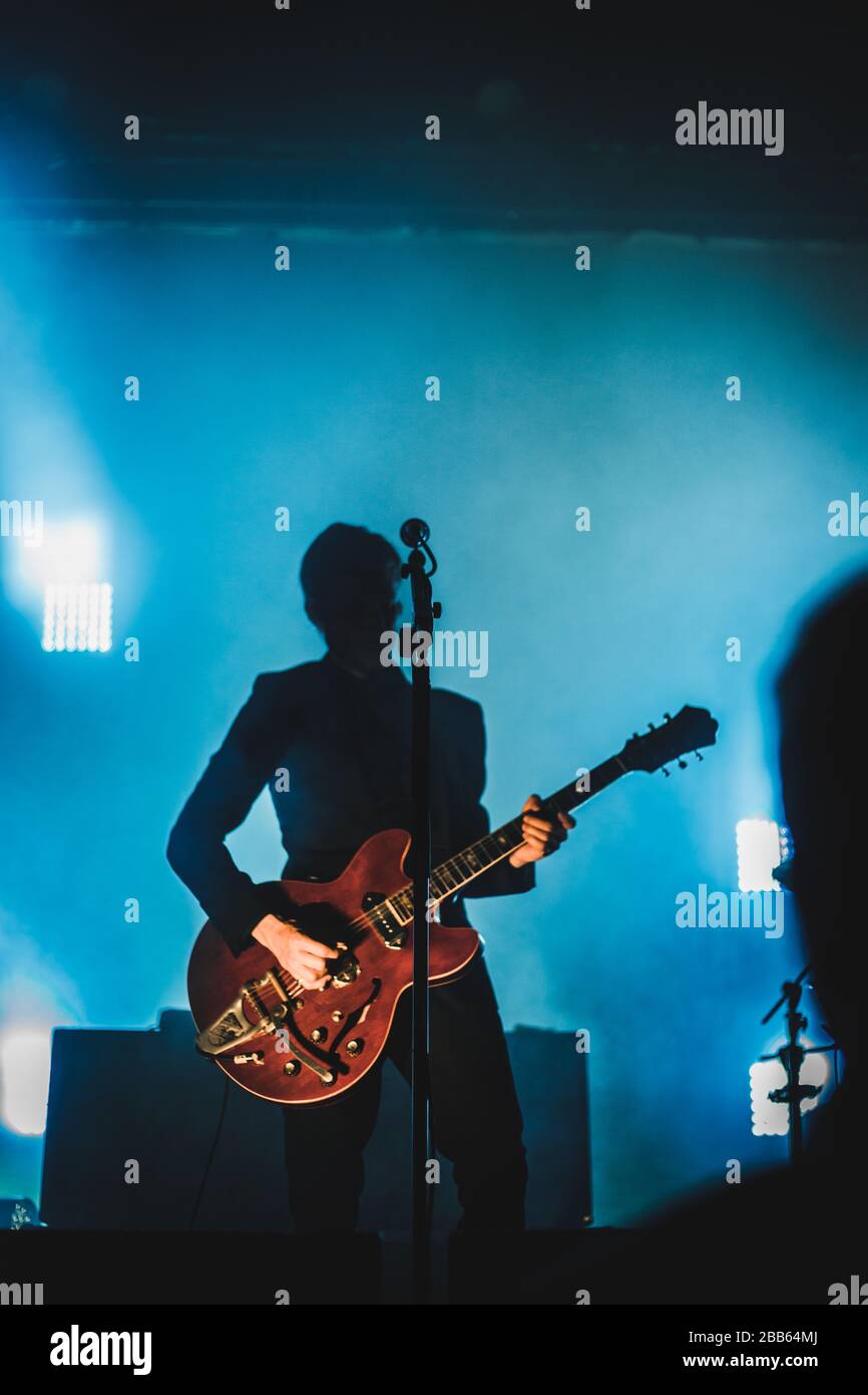 Silhouette di un uomo che suona la chitarra sul palco. Sfondo scuro, fumo, faretti Foto Stock