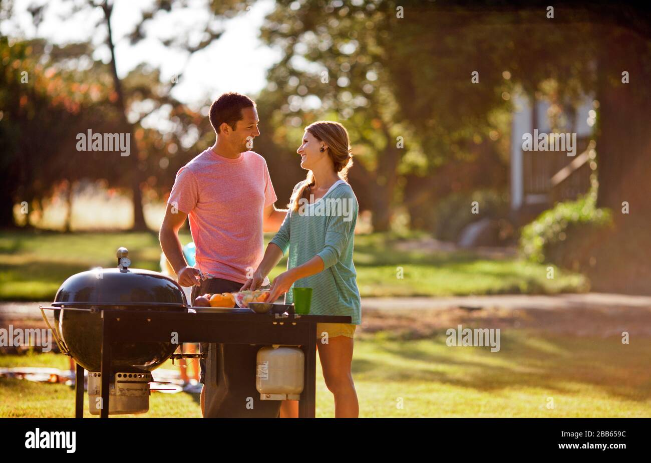 Coppia sorridente cottura su un barbecue nel loro back yard. Foto Stock