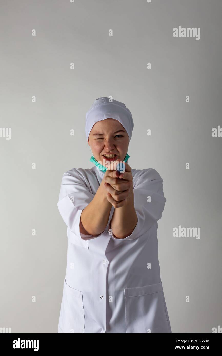 La ragazza in un cappotto medico tiene una siringa grande con liquido blu come una pistola Foto Stock