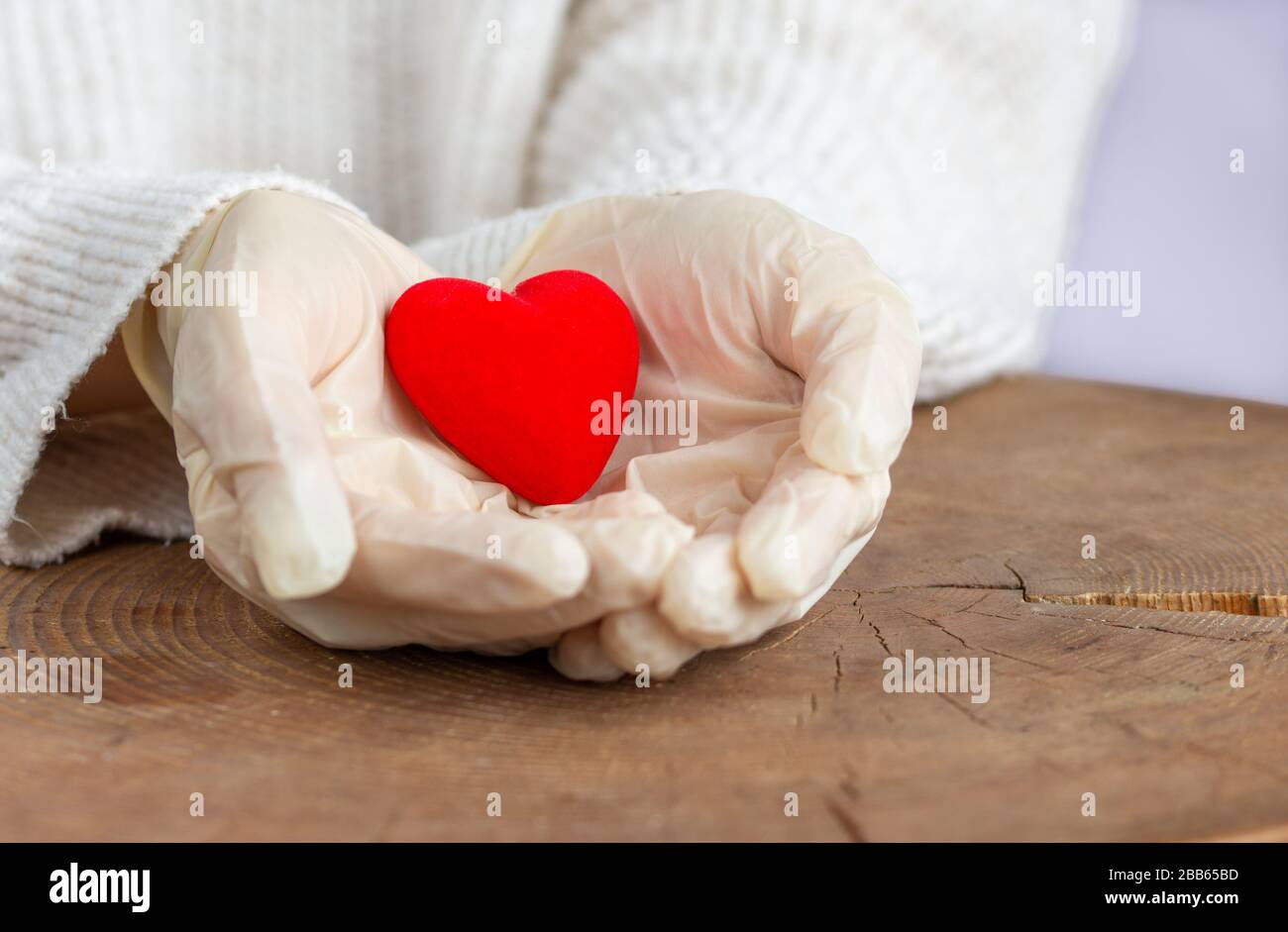 Concetto di stop virus, covid-19, sars. Cuore rosso nelle mani dell'uomo protetto da guanti medicinali. Foto Stock