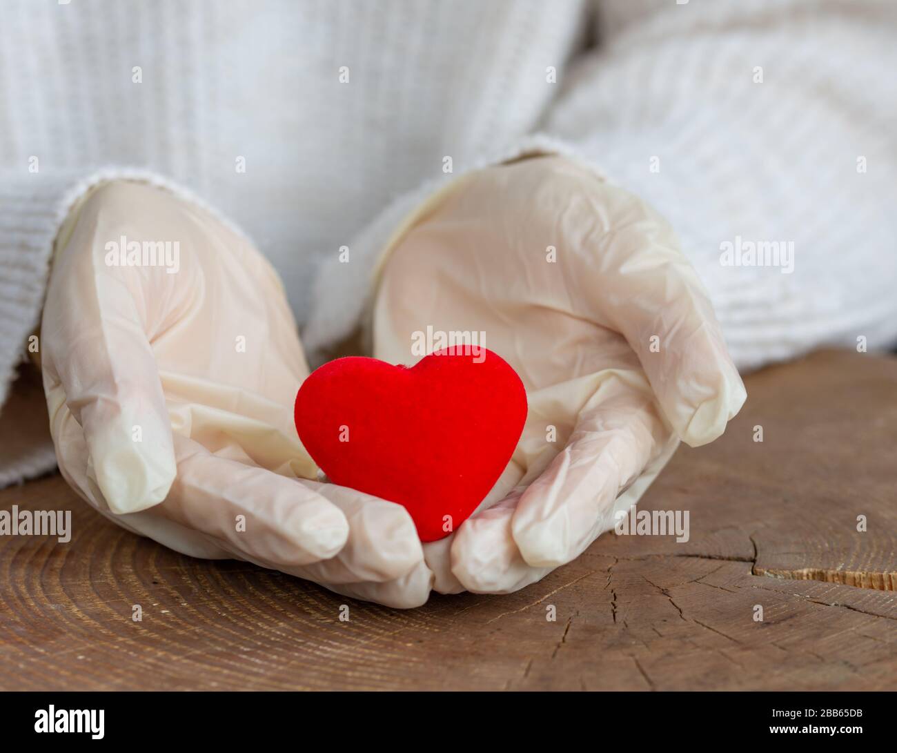 Concetto di stop virus, covid-19, sars. Cuore rosso nelle mani dell'uomo protetto da guanti medicinali. Foto Stock