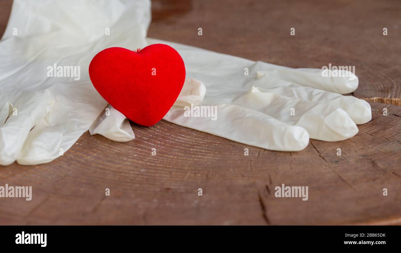 Concetto di stop virus, covid-19, sars. Guanti di cuore rosso e bianchi sul tavolo di legno. Foto Stock