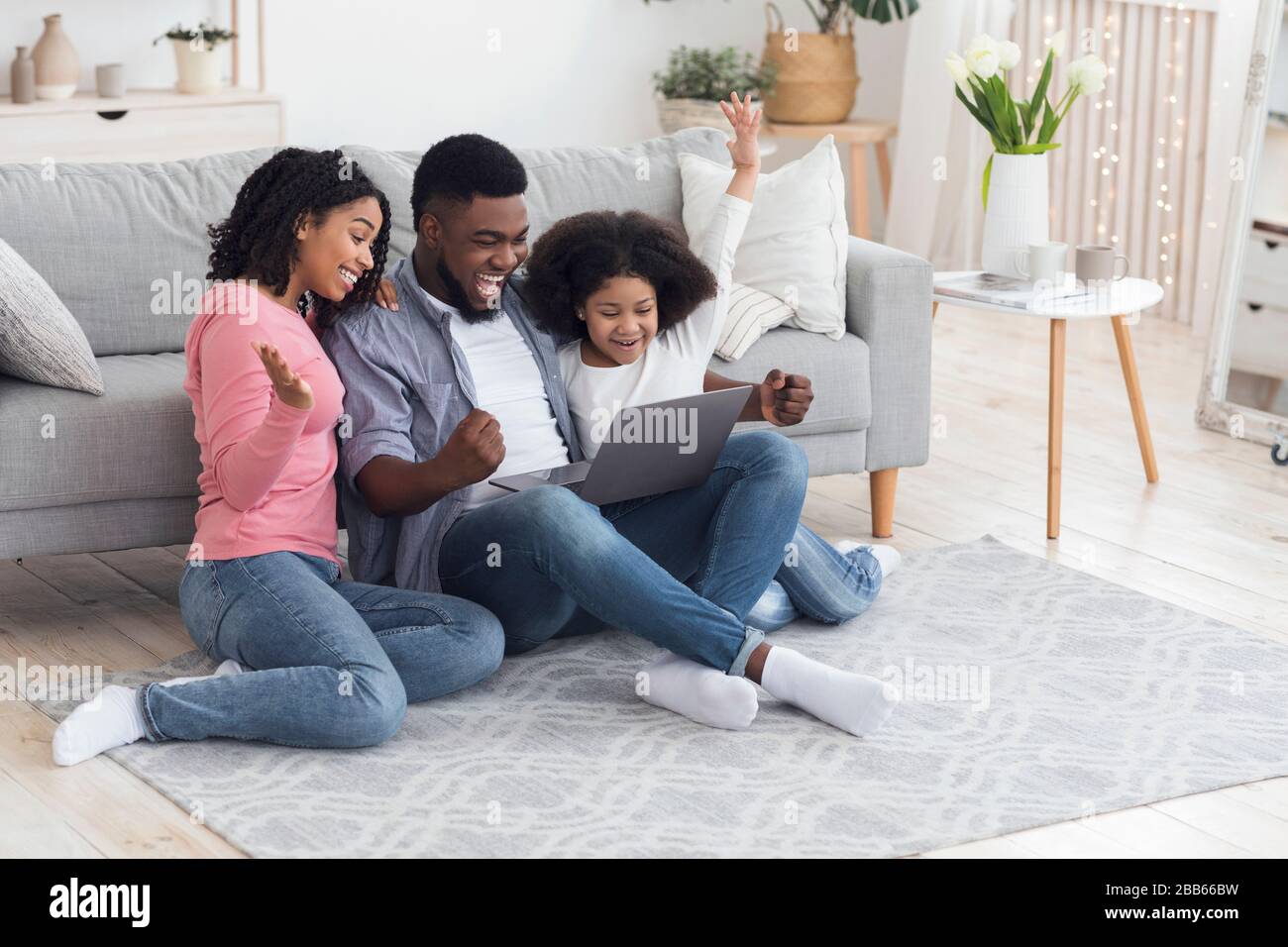 Madre africana, padre e figlia celebrano il successo con il laptop a casa Foto Stock