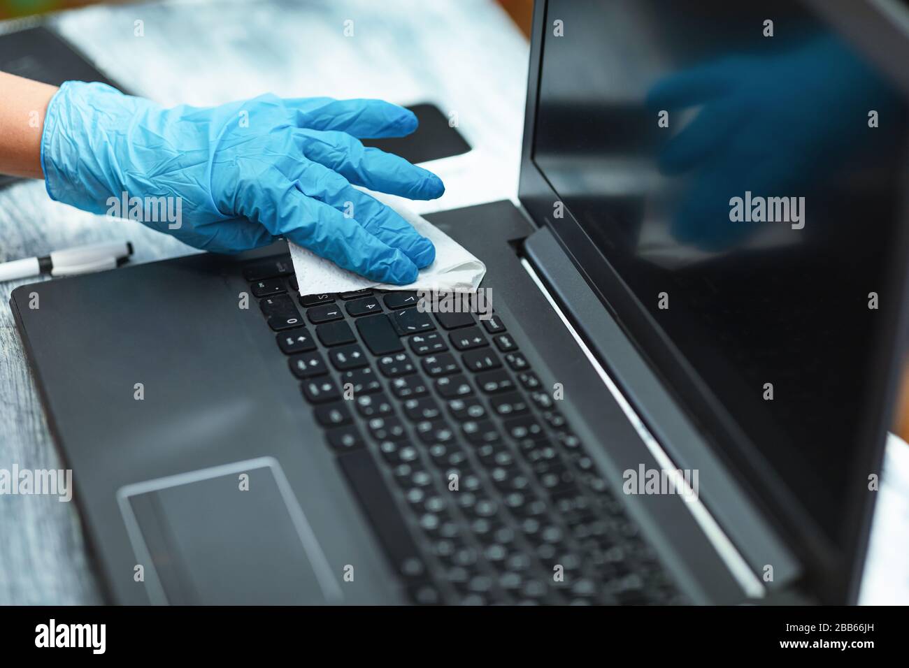 Donna in quarantena indossando guanti per la pulizia del computer portatile Foto Stock