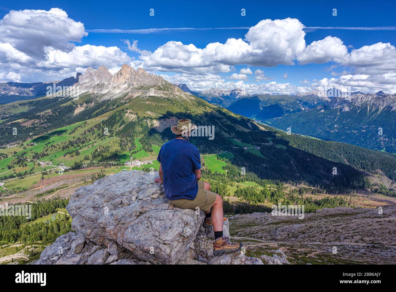 Escursionista seduto in cima a Pulpito di cima Papa che guarda alle montagne di Rosengarten, Alto Adige, Italia Foto Stock