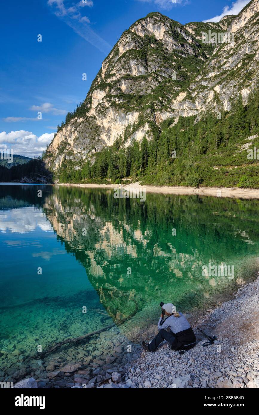 Donna seduta sul Lago di Braies scatta una foto, Alto Adige, Italia Foto Stock