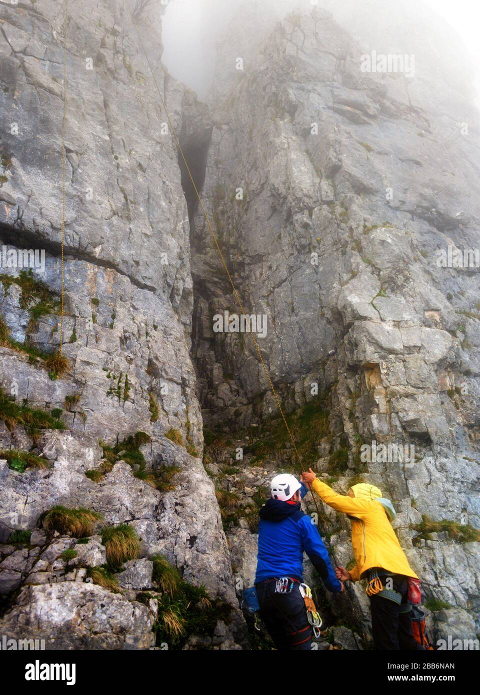 Uomo e donna montagna arrampicata nella nebbia, Ebenalp, Svizzera Foto Stock