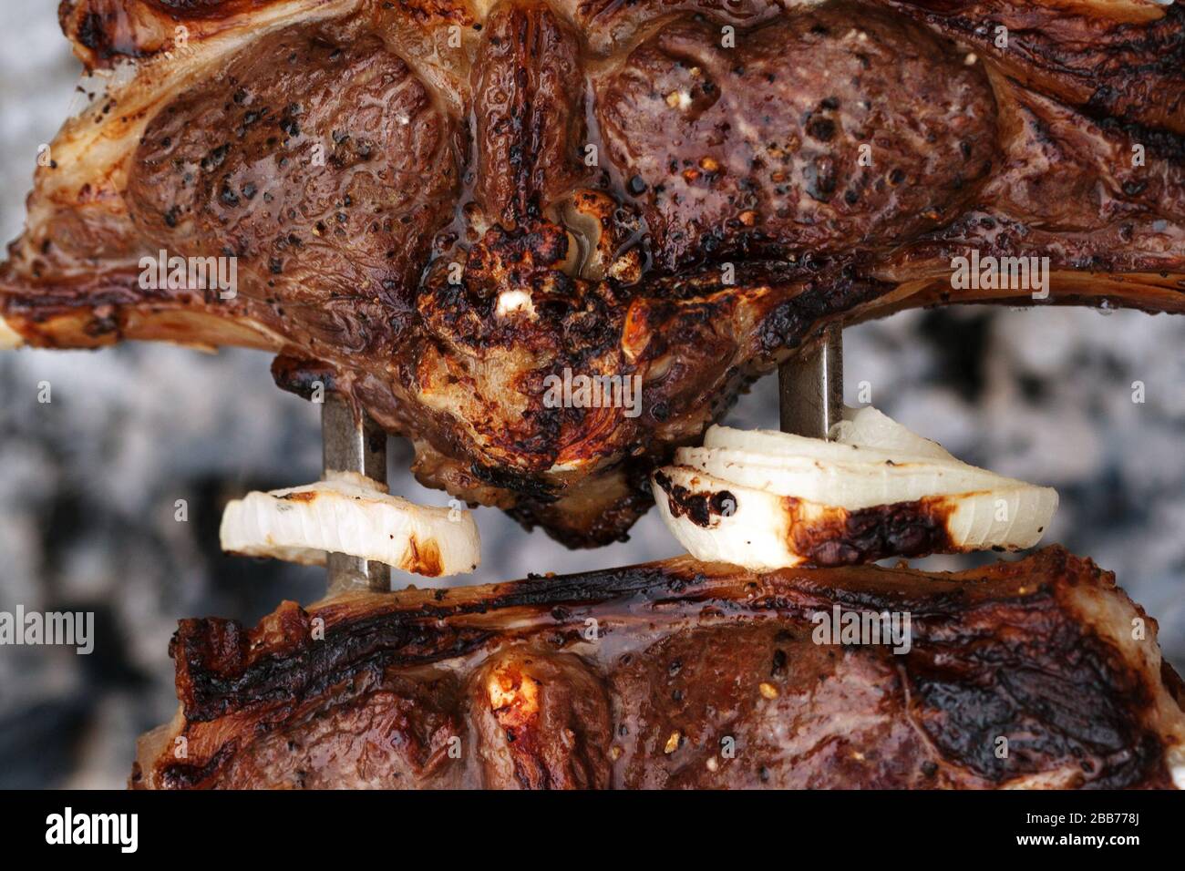 Anelli di cipolla e shashlik di agnello con crosta fritta su spiedino barbecue. Cucina all'aperto su falò. Vista ravvicinata. Foto Stock