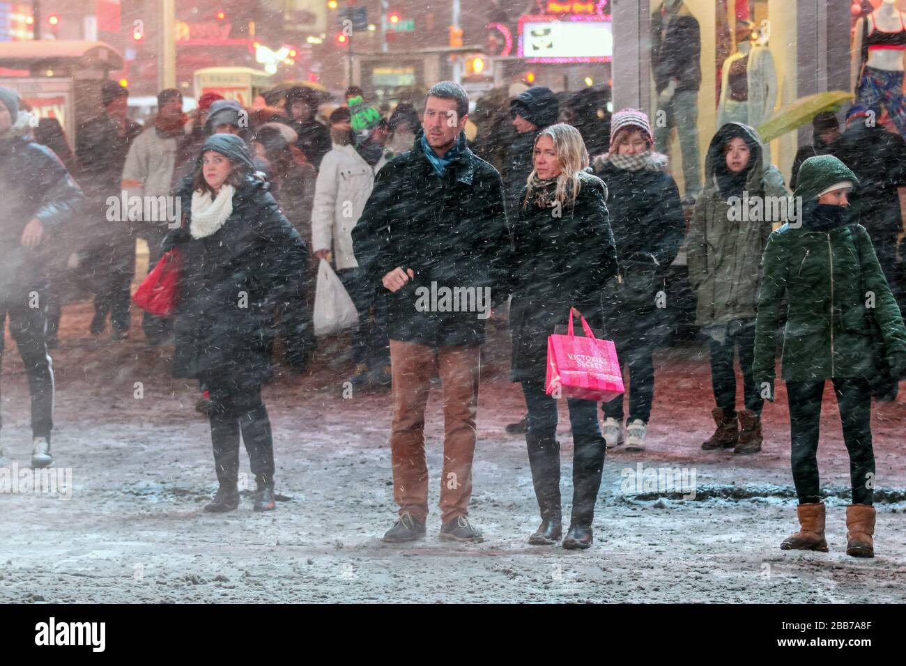 Persone in piedi a luce rossa durante la neve Blizzard a Times Square, New York City, USA Foto Stock