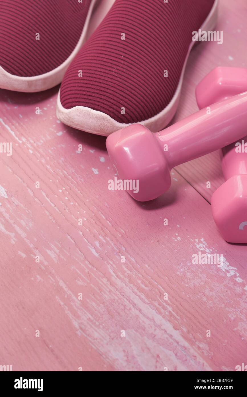 Primo piano di dumbbell, scarpe e acqua sul tappetino da ginnastica. Foto Stock