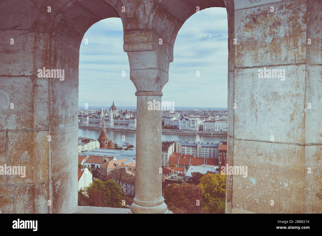 Paesaggio urbano di Budapest, Ungheria fotografato attraverso la finestra dell'arco del Bastione dei pescatori. Palazzo del Parlamento ungherese, Orszaghaz, sullo sfondo dell'altro lato del Danubio. Foto Stock