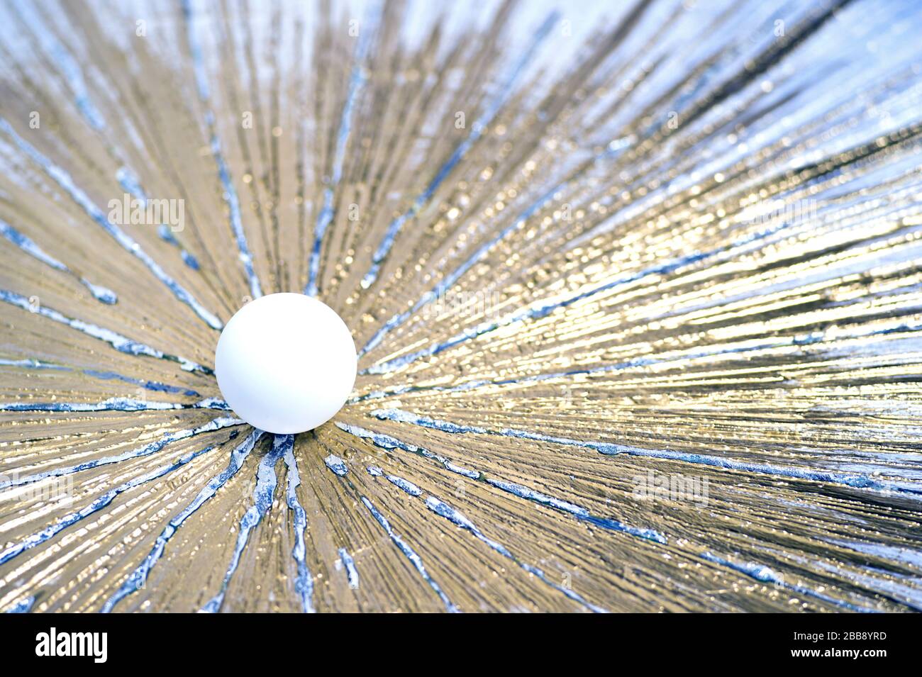 Una pallina da ping pong bianca attraversa una superficie in oro metallico, simboleggiando velocità e potenza. Disegno concettuale per etichette, rivestimenti per ping pong. Foto Stock