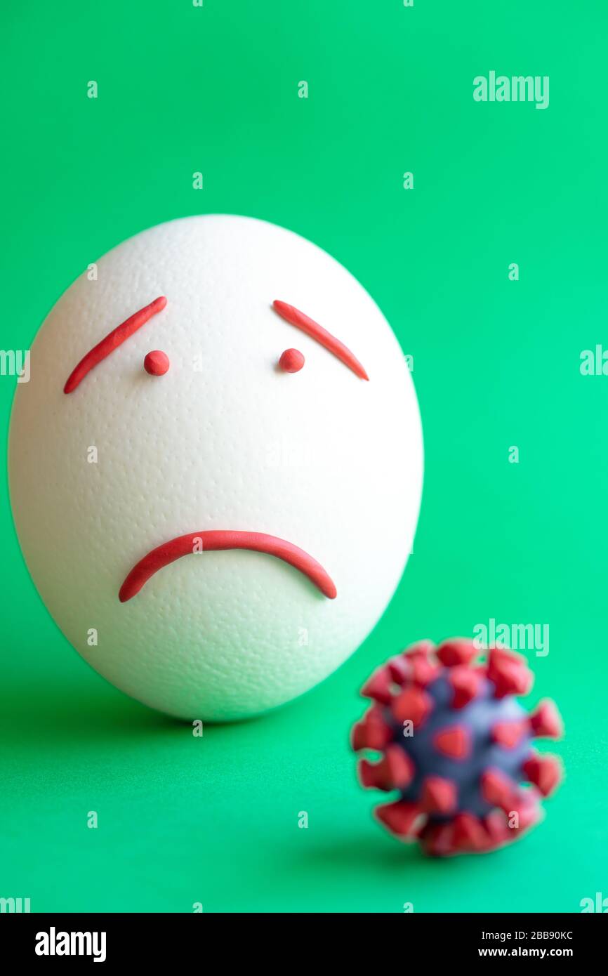 Modello di coronavirus plastificato e isolato di uovo su sfondo verde. Modello plastilina di coronavirus e uovo di pasqua raffigurante paura e tristezza Foto Stock