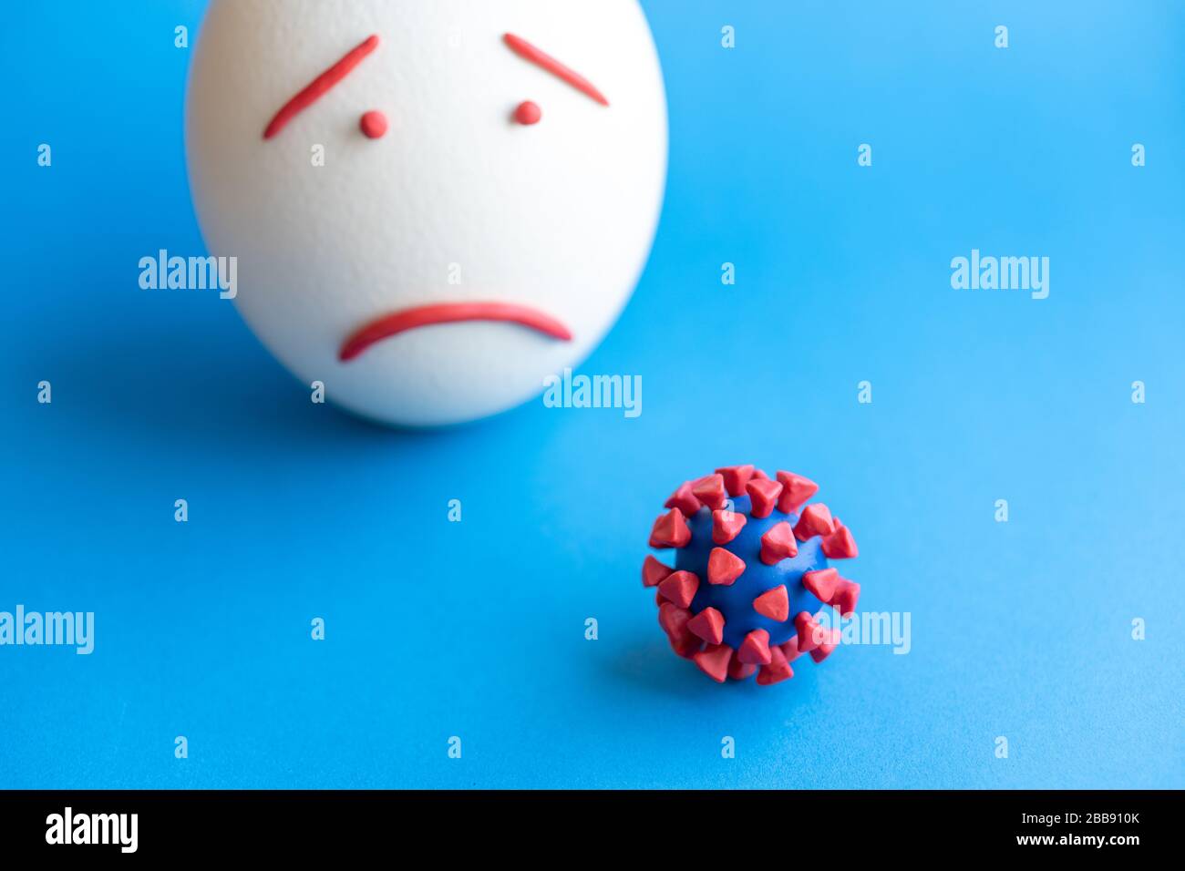 Modello di coronavirus plastificato e isolato di uovo su sfondo blu. Modello plastilina di coronavirus e uovo di pasqua raffigurante paura e tristezza. Grande Foto Stock