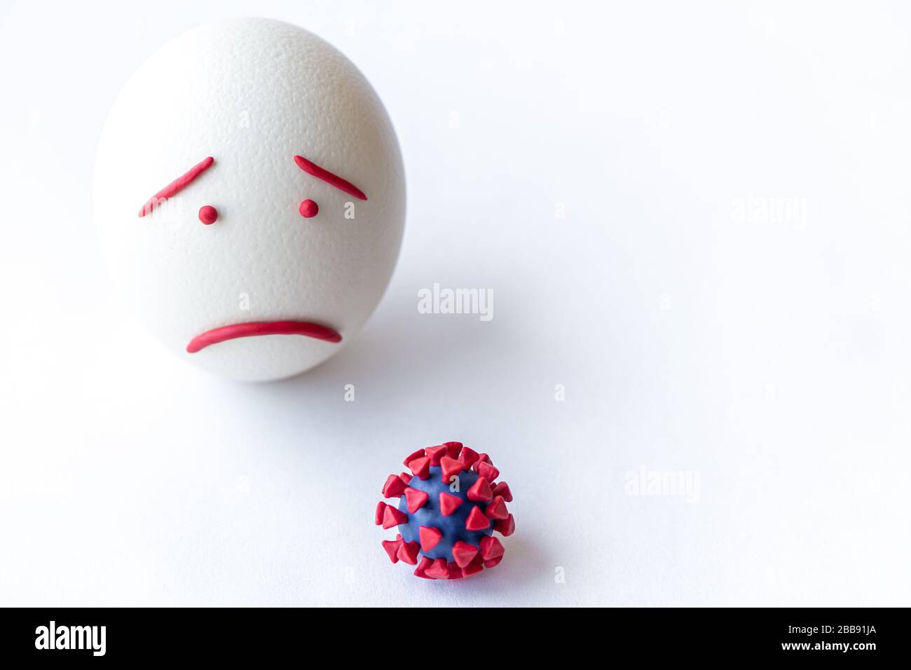 Modello di coronavirus plastificato e isolato di uovo su sfondo bianco. Modello plastilina di coronavirus e uovo di pasqua raffigurante paura e tristezza Foto Stock