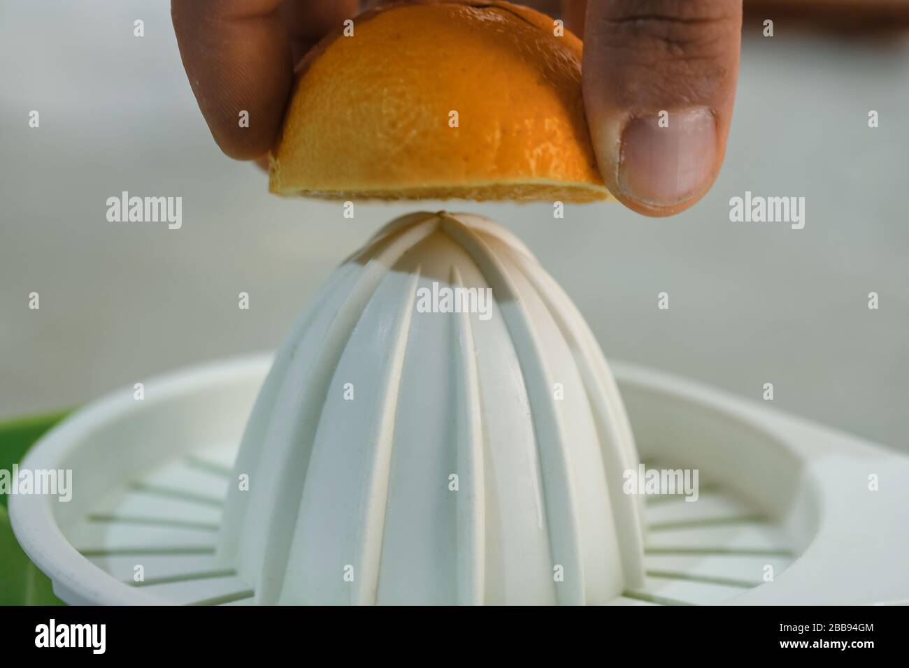 Mano dell'uomo spremere frutta fresca arancione sulla centrifuga, sana prima colazione preparare, vitamina Foto Stock