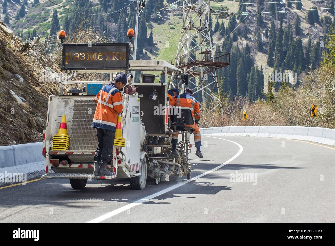 Pittura della linea di traffico. I lavoratori stanno dipingendo la linea bianca della strada sulla strada di montagna. Foto Stock