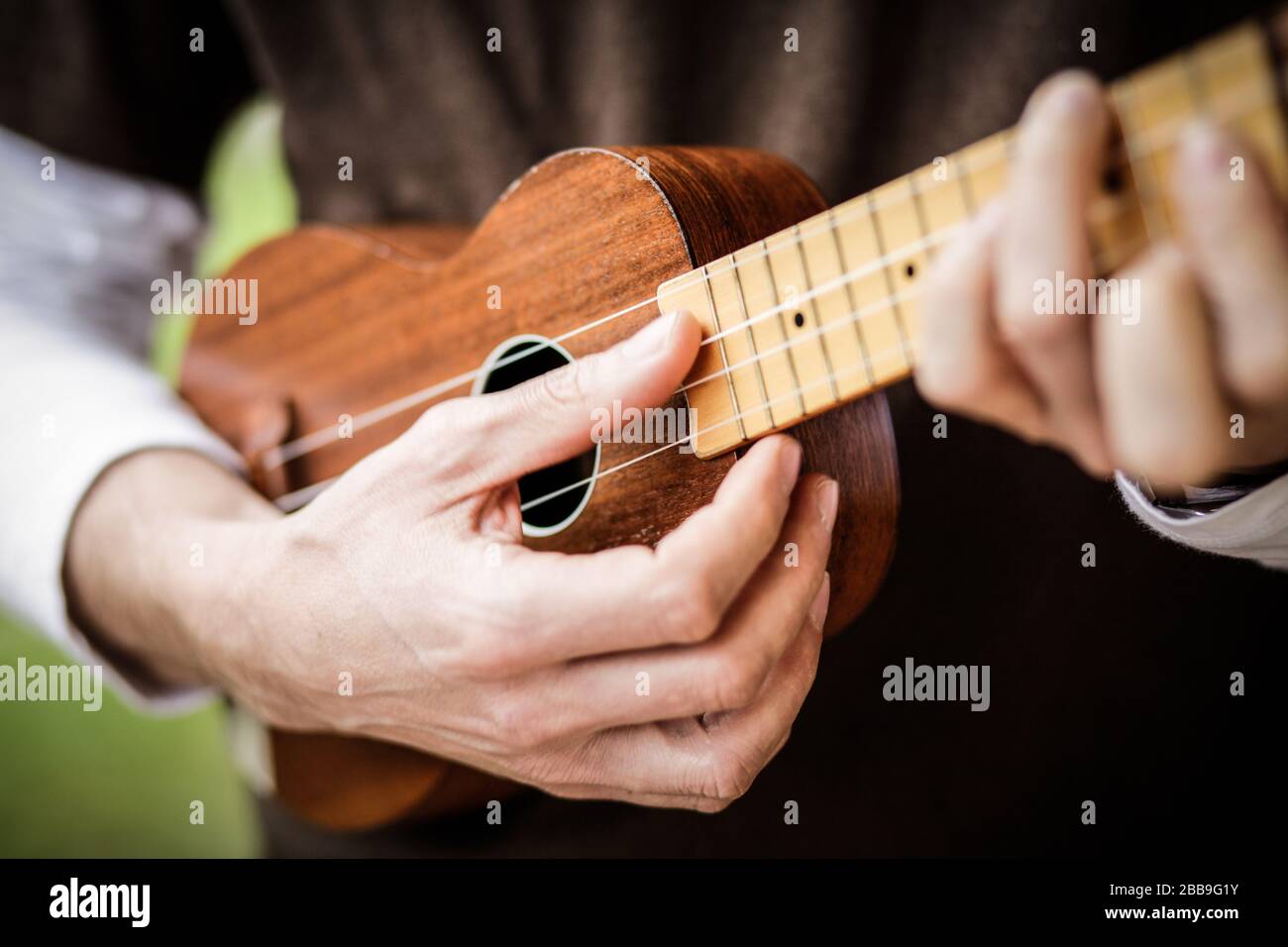 le mani del musicista giocano l'ukulele acustico Foto Stock