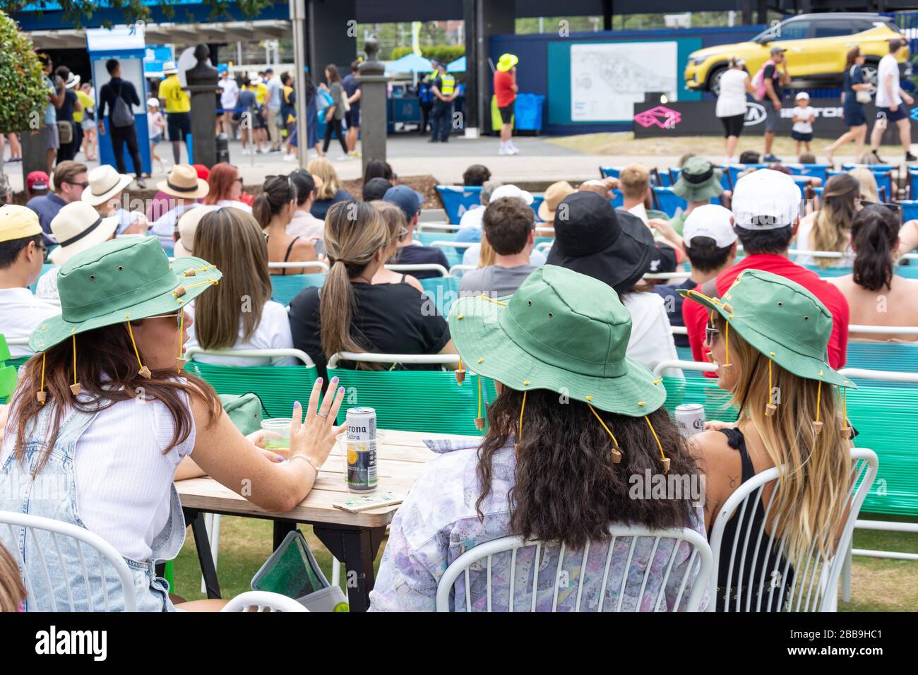 Giovani donne che indossano cappelli da sughero a disco floppy in Garden Square al torneo di tennis Melbourne Open 2020, City Central, Melbourne, Victoria, Australia Foto Stock