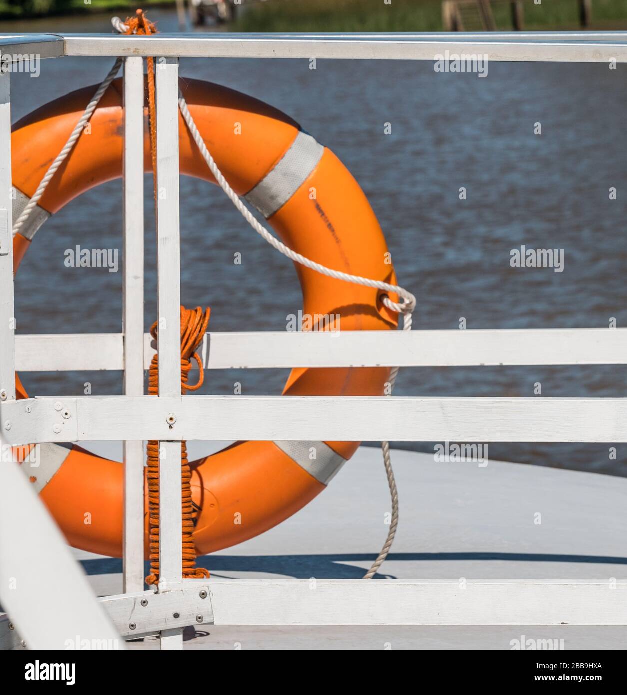 Foto di una barriera di guardia su una barca con un salvagente arancione ad essa collegato. Foto Stock