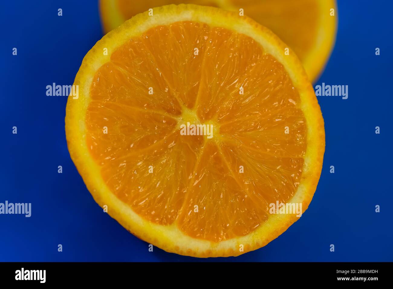 Semi tagliati succosa arancia italiana dettagli su sfondo blu, frutta di stagione Foto Stock