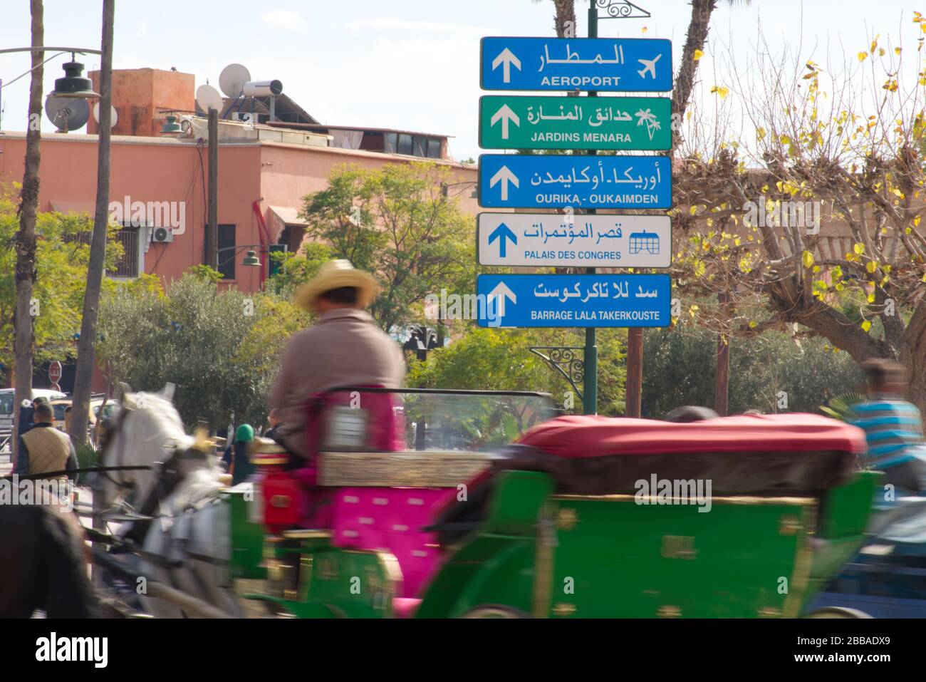 Un segno direzionale a Marrakech, scritto in arabo e francese. Circondato da mezzi di trasporto in movimento sfocato, suggerendo velocità. Foto Stock