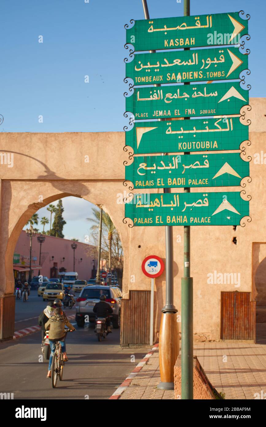 Un segno direzionale a Marrakech, scritto in arabo e francese. Circondato da mezzi di trasporto in movimento sfocato, suggerendo velocità. Foto Stock