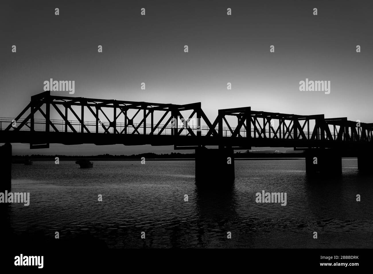 Il Ponte storico della Ferrovia di Tauranga si staglia alla luce della mattina presto contro l'alba in bianco e nero. Foto Stock