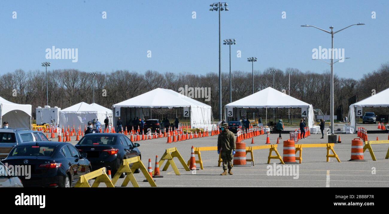 I veicoli attendono di essere diretti verso una corsia in un sito di campionamento drive-through COVID-19 a Stony Brook, N. Y., 18 marzo 2020. I siti Drive-Thru per il prelievo dei campioni sono stati configurati come parte della risposta multiagenzia di New York a COVID-19. (Immagine modificata in conformità con HIPAA, targhe oscurate). (STATI UNITI Air National Guard foto di Senior Airman Sean Madden) Foto Stock