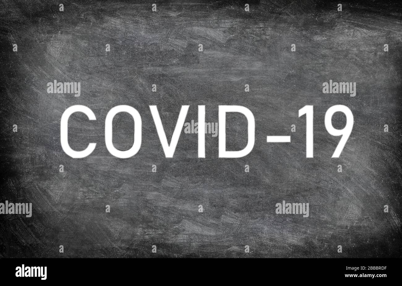 COVID-19 testo in calck bianco su lavagna nera texture grunge sfondo in difficoltà. Disegno grafico del disegno del virus corona con titolo. Foto Stock