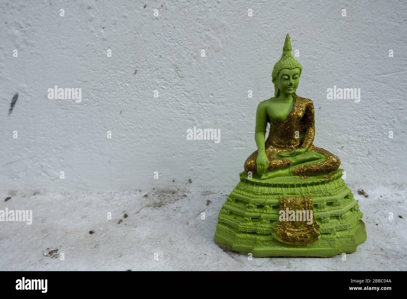 Statua del Buddha verde smeraldo in miniatura sullo sfondo bianco Foto Stock