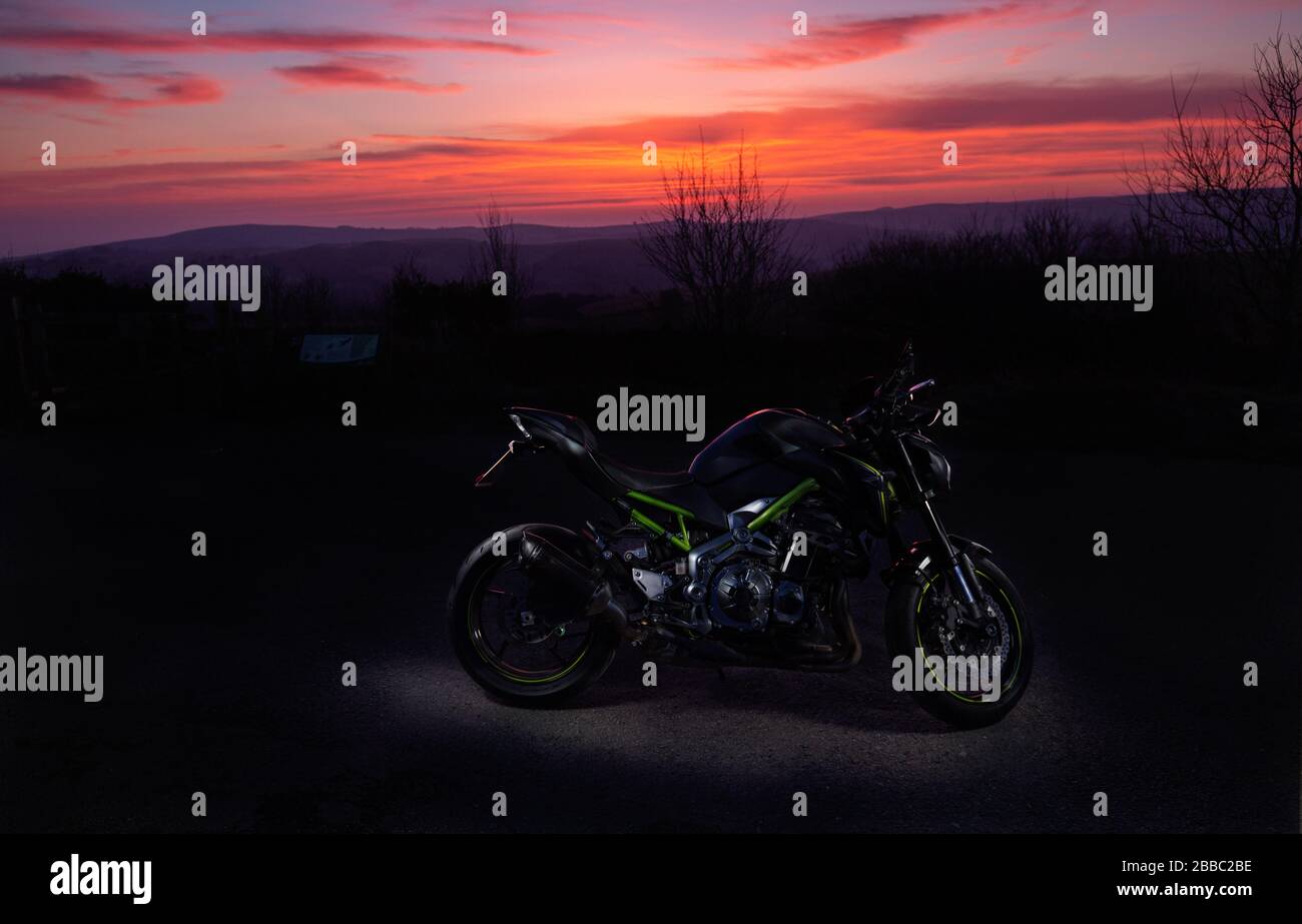 Moderna moto sportiva parcheggiata a scenografica loacation rurale con Vvid rosso crepuscolo cielo Foto Stock