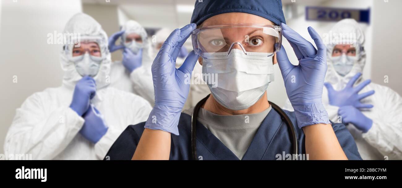 Squadra di medici o infermieri femminili e maschili che indossano l'Equiment protettivo personale nel corridoio dell'ospedale. Foto Stock