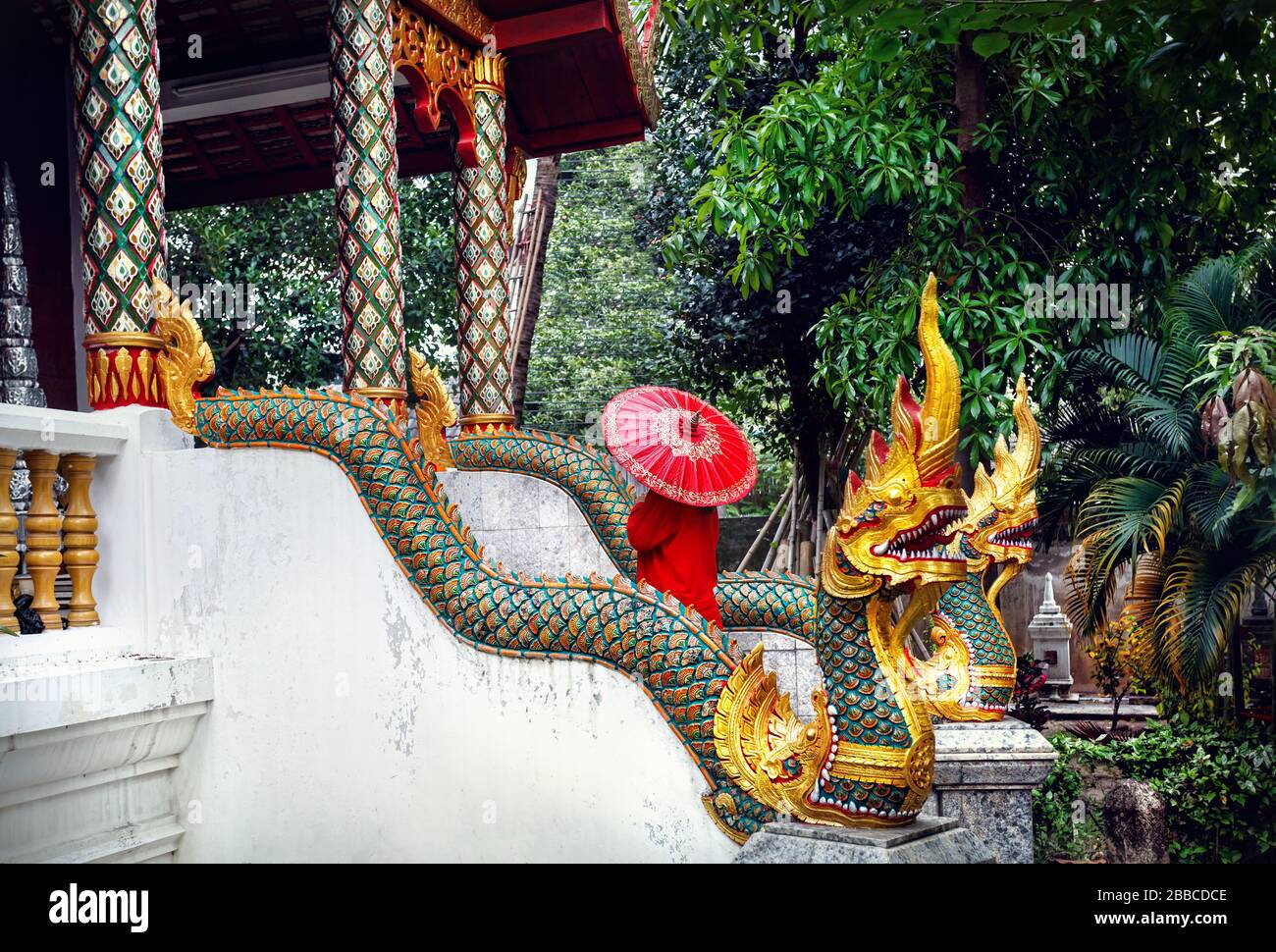 Donna con turistico rosso tailandese tradizionale ombrellone nel monastero del tempio con le statue del drago in Chiang Mai Thailandia Foto Stock