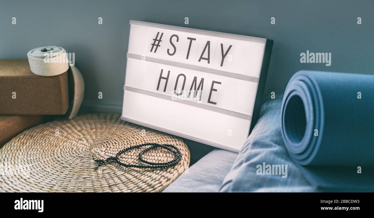 Coronavirus Yoga a casa segno scatola luminosa con testo hashtag hashtag STAYHOME incandescente in luce con tappetino da sforzo, blocchi di sughero, cinghia di meditazione cuscini. Banner COVID-19 per promuovere l'isolamento di se stessi rimanendo a casa. Foto Stock