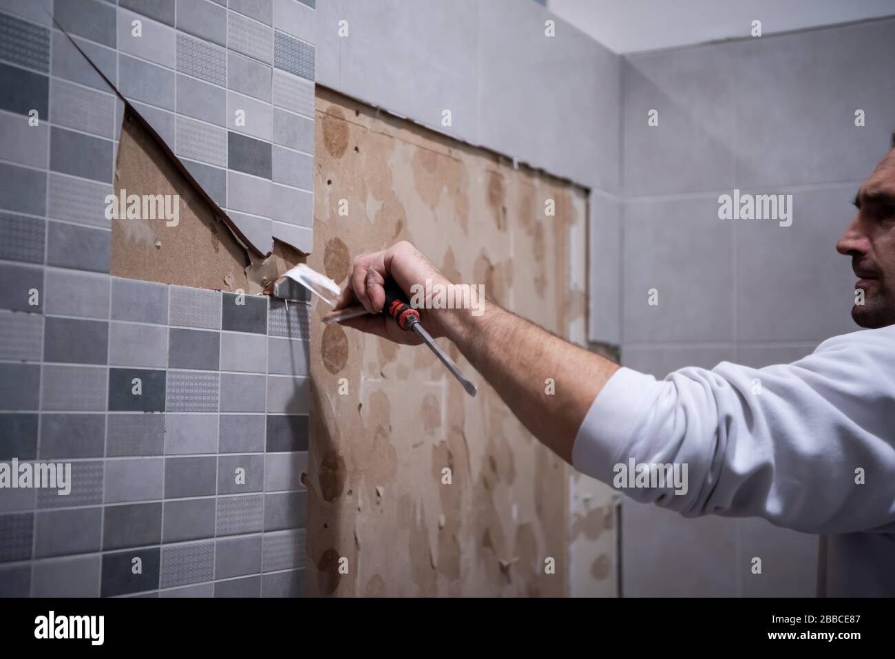 lavoratore professionale rimuovere le vecchie piastrelle demolite in un  bagno con martello e scalpello Foto stock - Alamy