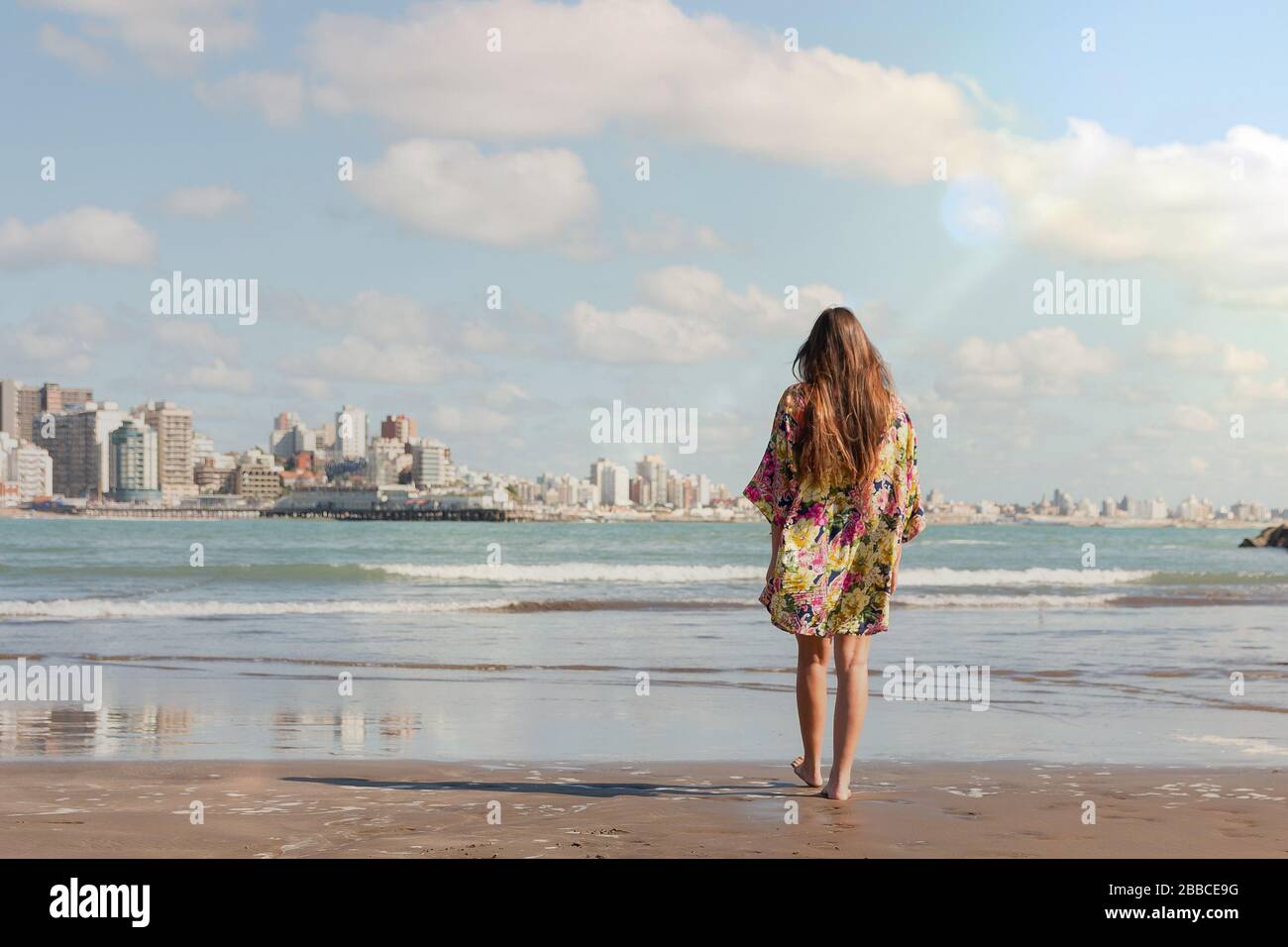 Giovane donna che cammina verso il mare in spiaggia Foto Stock