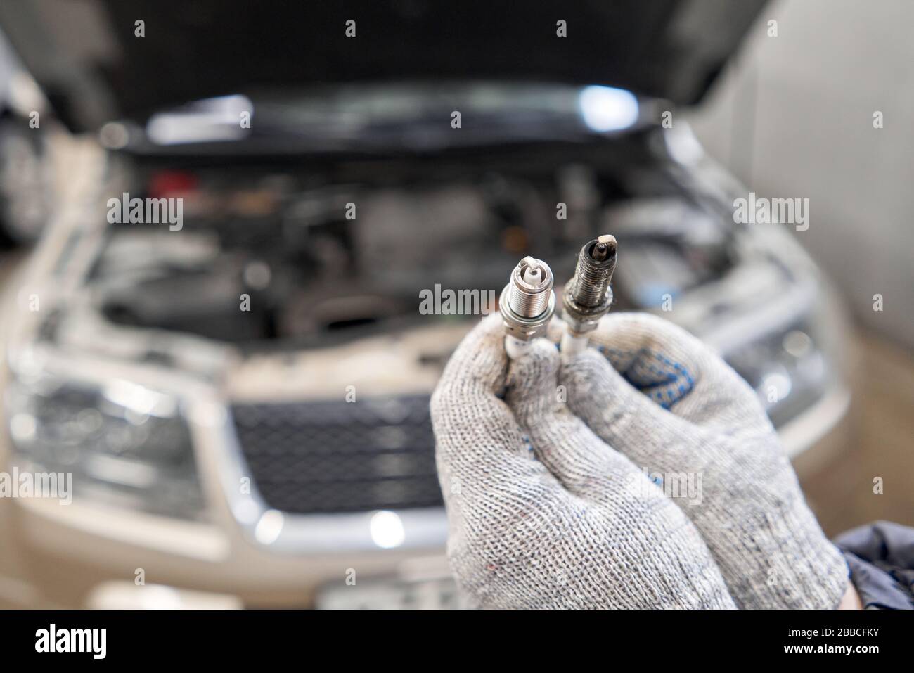 Candele vecchie e nuove. Confronto delle candele di accensione la manutenzione del motore, sulle mani di un meccanico. Foto Stock