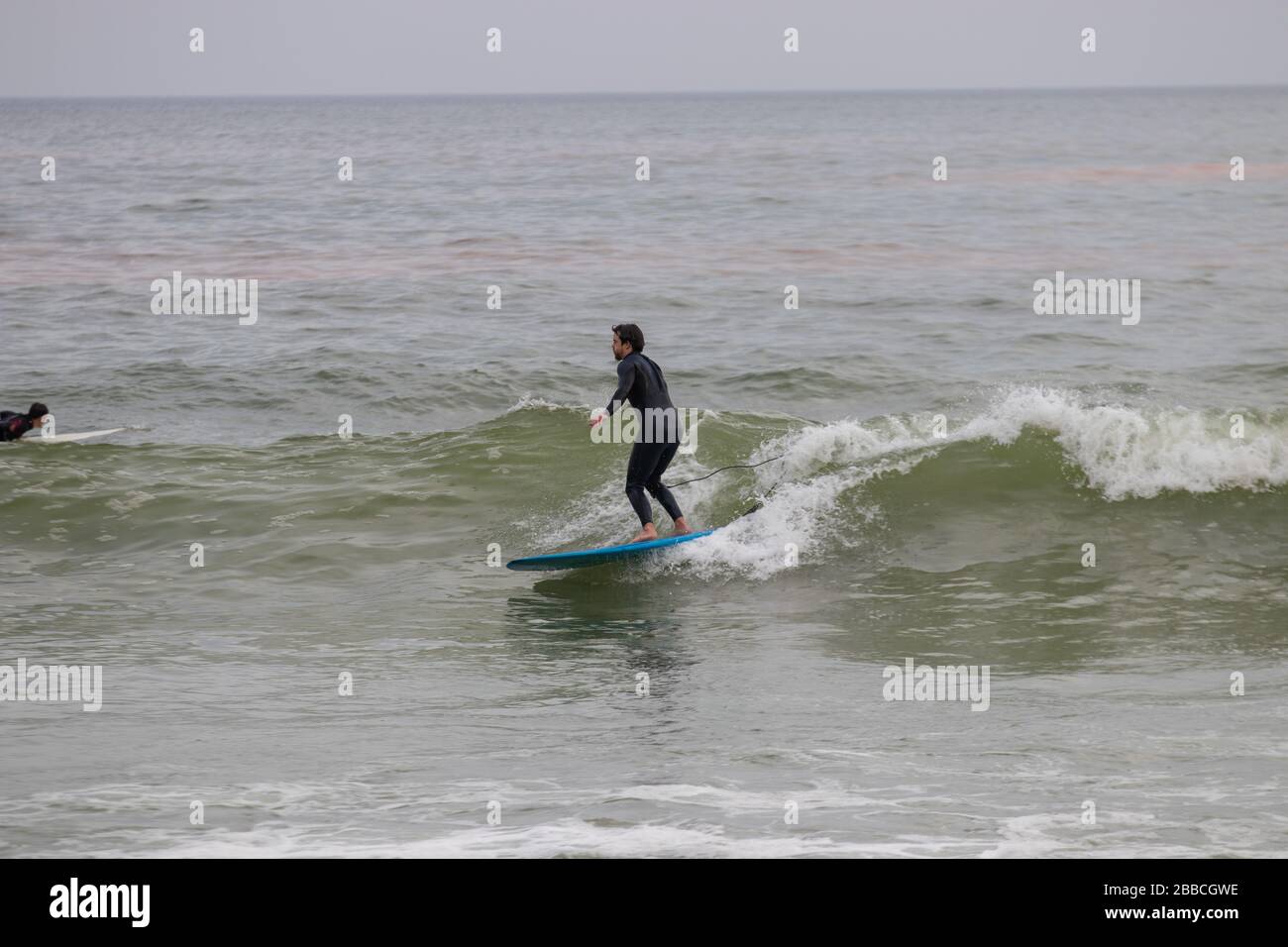 Muizenberg, Sudafrica. Marzo 2020. Un surfista guida una piccola onda in una popolare spiaggia di surf locale a Città del Capo. Foto Stock